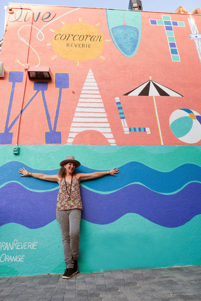 Maxine Orange in front of the Mural she painted at the Corcoran Reverie Seagrove Beach office on 30a Santa Rosa Beach FL